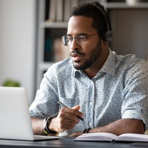 Focused,Young,African,Businessman,Wear,Headphones,Study,Online,Watching,Webinar